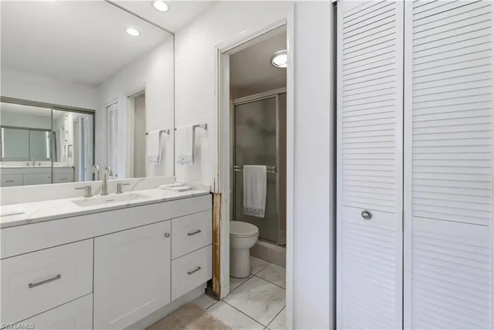 Bathroom featuring a closet, vanity, a shower stall, recessed lighting, and light marble finish floors