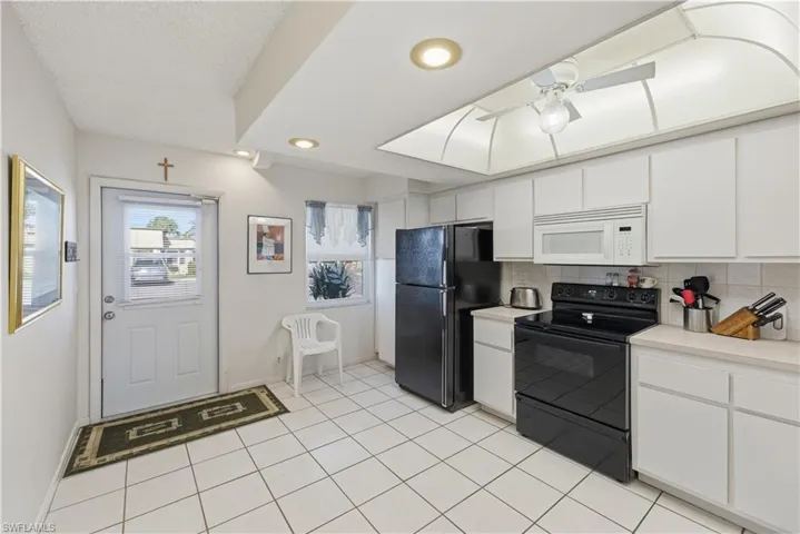 Kitchen featuring black appliances, white cabinetry, light countertops, tasteful backsplash, and recessed lighting