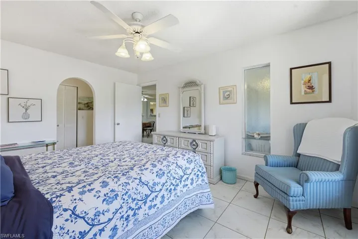 Bedroom featuring a closet, arched walkways, a ceiling fan, and light marble finish flooring