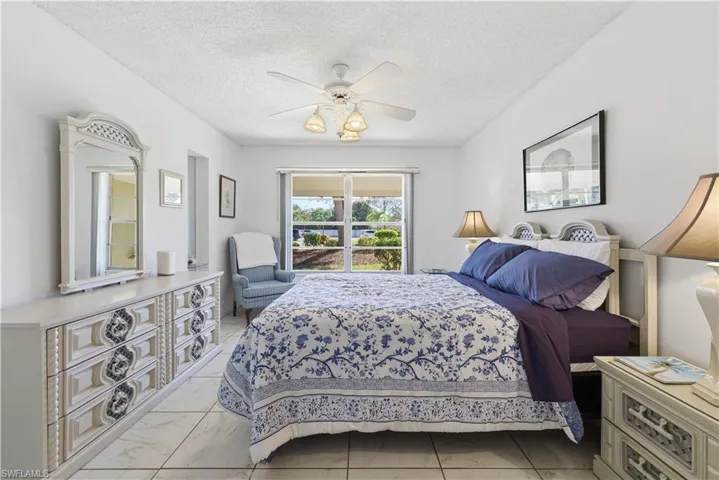 Bedroom with a textured ceiling, a ceiling fan, and light marble finish flooring