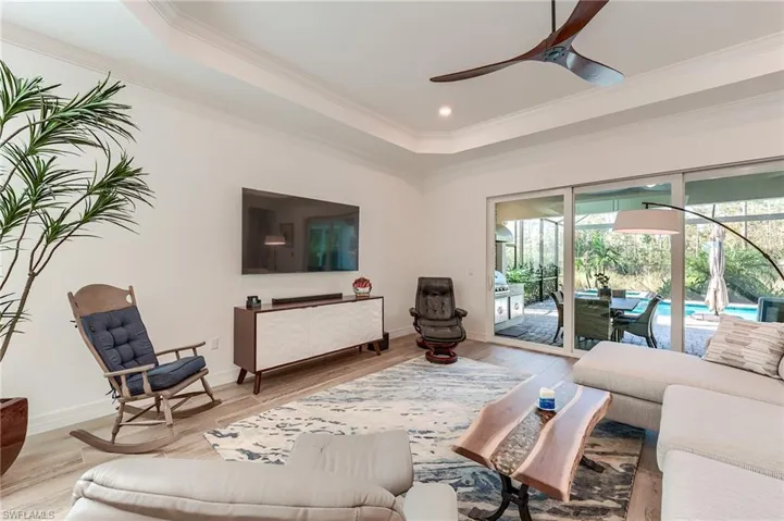 Living room featuring wood-type flooring, ceiling fan, and crown molding