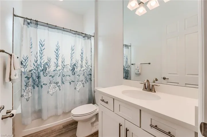 Full bathroom featuring hardwood / wood-style floors, vanity, toilet, and shower / bath combo