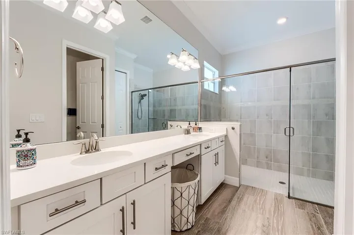 Bathroom featuring hardwood / wood-style floors, vanity, an enclosed shower, and crown molding