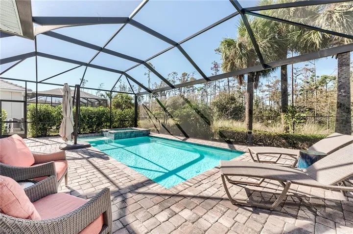 View of pool with an in ground hot tub, a patio, and glass enclosure