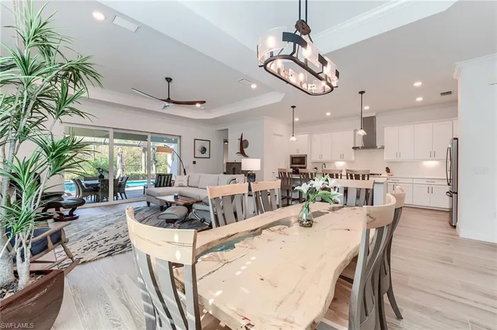 Dining area with ceiling fan with notable chandelier, crown molding, and light hardwood / wood-style flooring