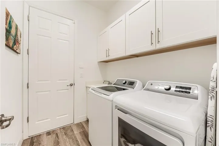 Washroom featuring washing machine and clothes dryer, cabinets, sink, and light hardwood / wood-style floors