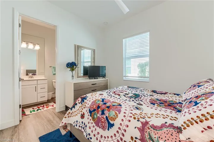 Bedroom with ensuite bath, ceiling fan, sink, and light wood-type flooring