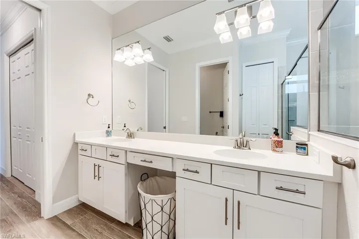 Bathroom featuring hardwood / wood-style floors, vanity, walk in shower, and crown molding