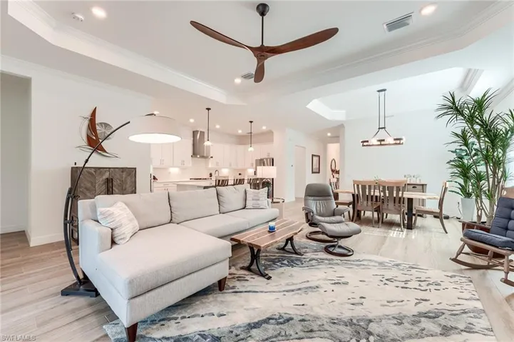 Living room featuring light hardwood / wood-style floors, a raised ceiling, and crown molding