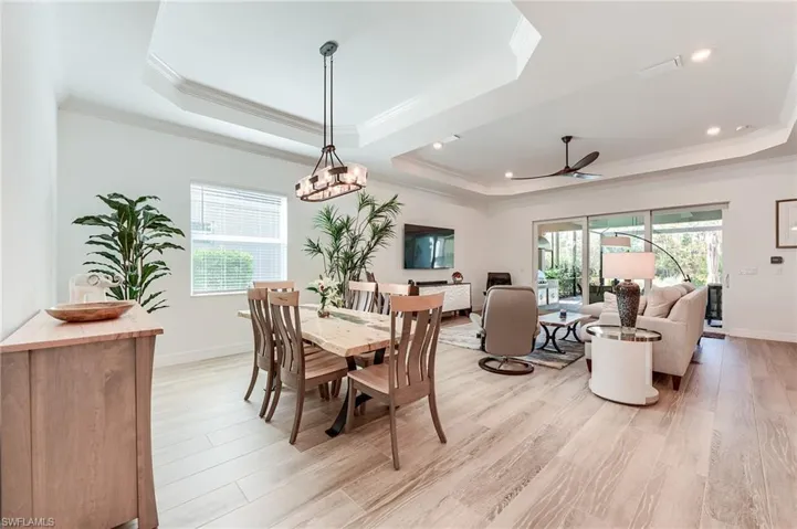 Dining area with light hardwood / wood-style floors, a raised ceiling, and plenty of natural light