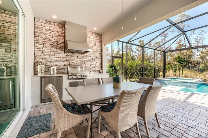 View of patio featuring an in ground hot tub, an outdoor kitchen, area for grilling, and a lanai