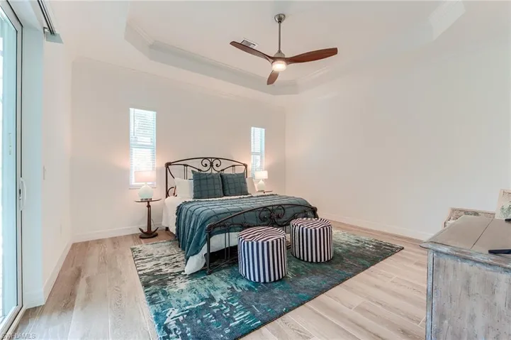 Bedroom featuring a raised ceiling, hardwood / wood-style flooring, ceiling fan, and ornamental molding