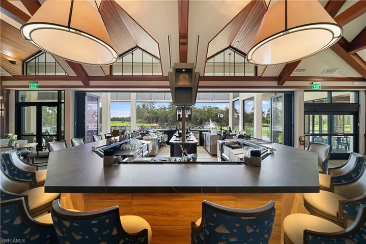 Bar with dark countertops, hanging light fixtures, and a high ceiling