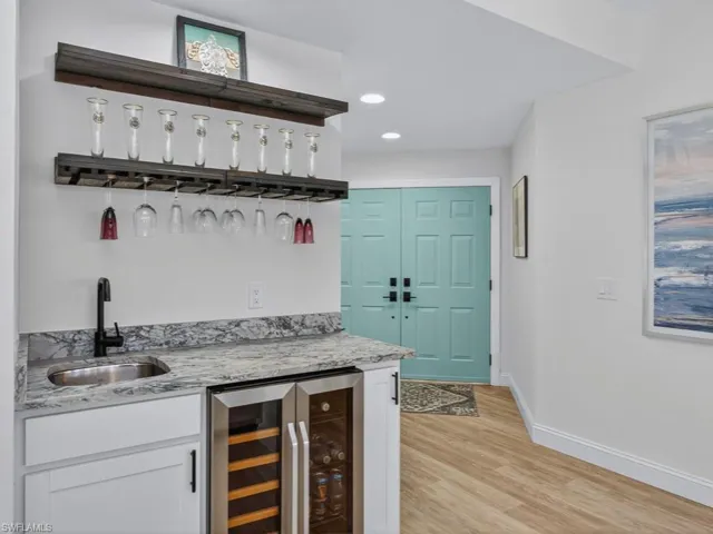 Indoor wet bar featuring white cabinets, beverage cooler, open shelves, recessed lighting, and light stone countertops