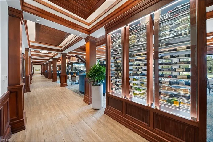 Hallway with decorative columns, crown molding, and light wood-style flooring