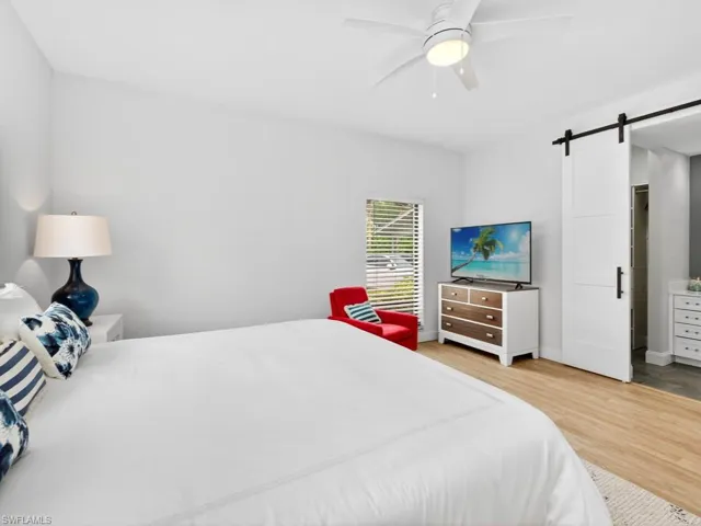 Bedroom featuring a barn door, light wood finished floors, and ceiling fan