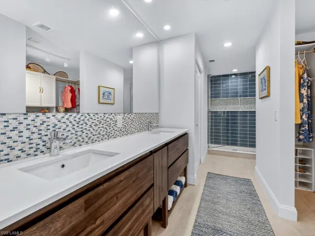 Full bath with a walk in closet, tasteful backsplash, a stall shower, double vanity, and recessed lighting