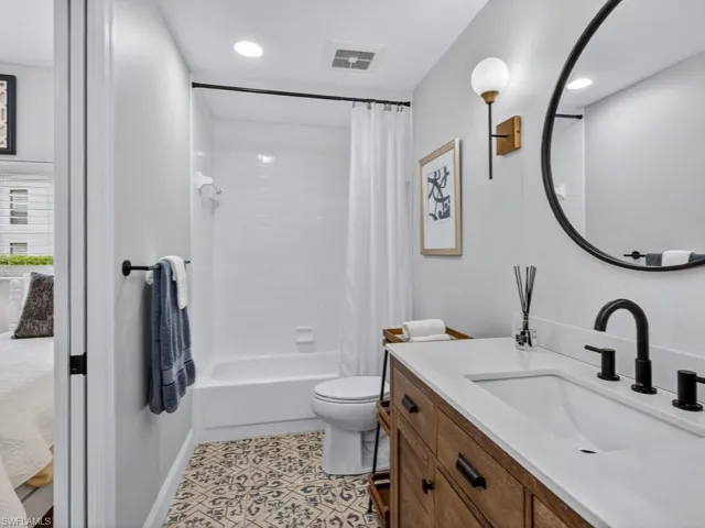Full bathroom with shower / bath combo with shower curtain, vanity, light tile patterned floors, and recessed lighting