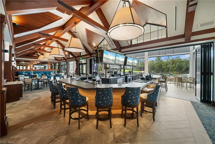 Bar featuring beam ceiling, dark countertops, pendant lighting, and high vaulted ceiling