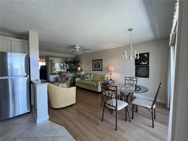 Dining area featuring ceiling fan, light wood-type flooring, a textured ceiling, and a chandelier