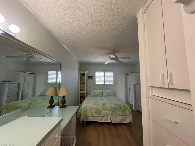 Bedroom featuring crown molding, a textured ceiling, dark wood finished floors, and ceiling fan