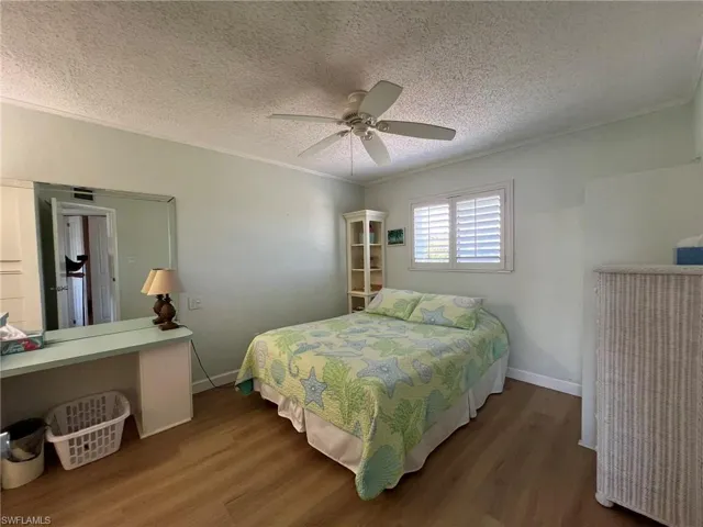 Bedroom featuring crown molding, dark wood-type flooring, a textured ceiling, and ceiling fan