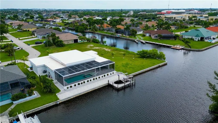 Modern waterfront residence featuring a screened-in pool and spa, private boat dock, and a spacious outdoor patio area