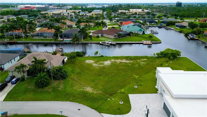 Expansive waterfront lot featuring extensive green space, mature palm trees, and direct canal access