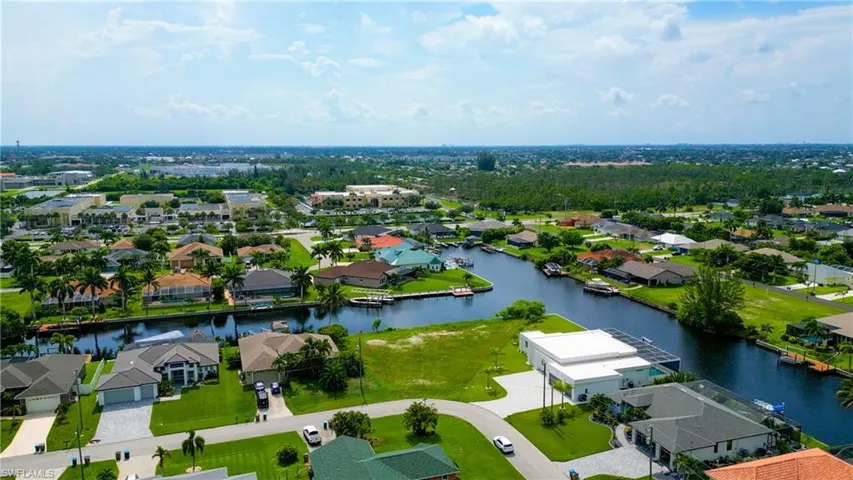 Expansive canal-front neighborhood featuring a variety of residential properties, lush green landscaping, and mature trees