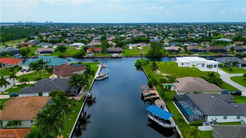 Canal-front property featuring a private boat dock with a covered lift and waterfront access
