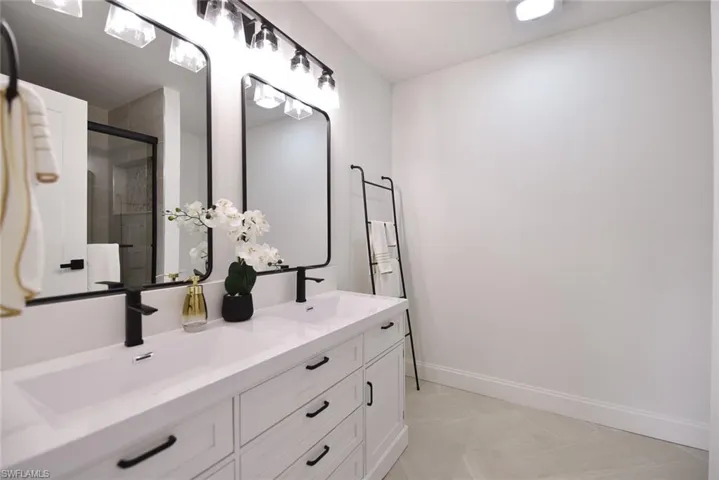 Full bathroom with double vanity and a shower stall