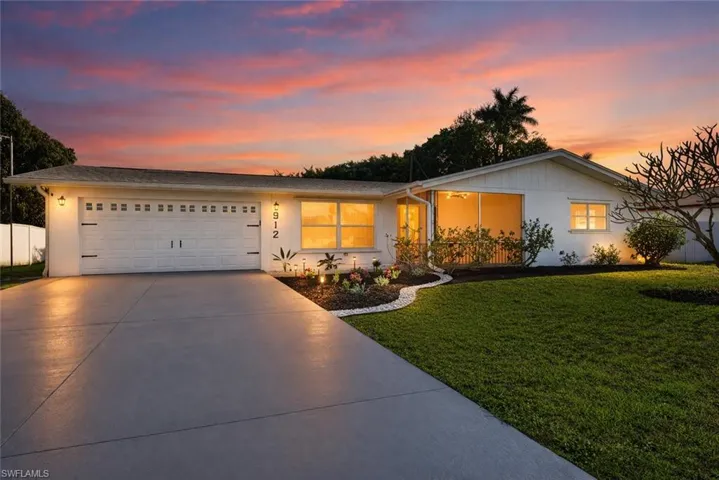 Ranch-style house with a garage, driveway, a front yard, and stucco siding