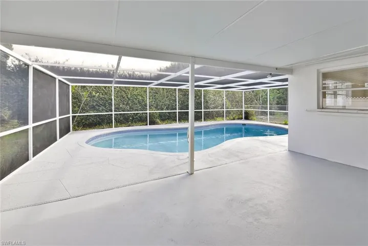 Swimming pool with a sunroom, a patio area, and a lanai