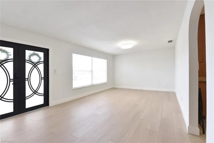 Entrance foyer with french doors, arched walkways, and light wood-style flooring