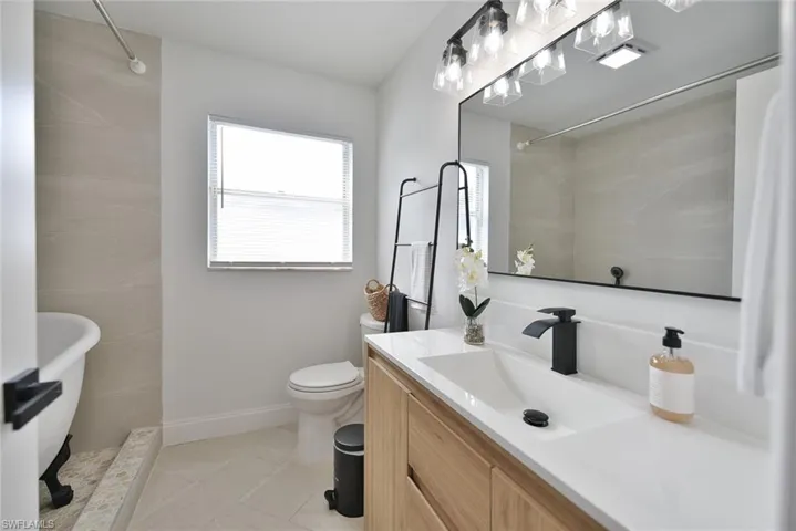 Full bath featuring vanity, a soaking tub, tiled shower, and light tile patterned flooring