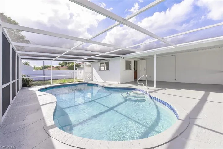 View of swimming pool with a sunroom, glass enclosure, and patio surround