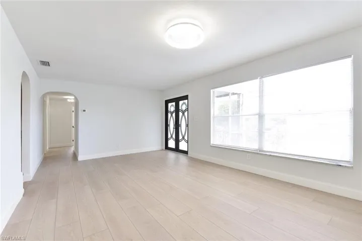 Spare room with arched walkways and light wood finished floors