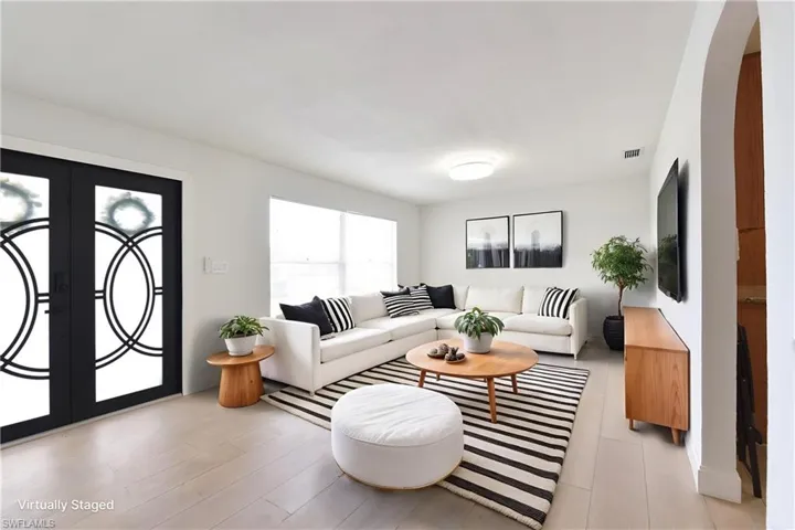 Living room featuring french doors, arched walkways, and light wood-style floors