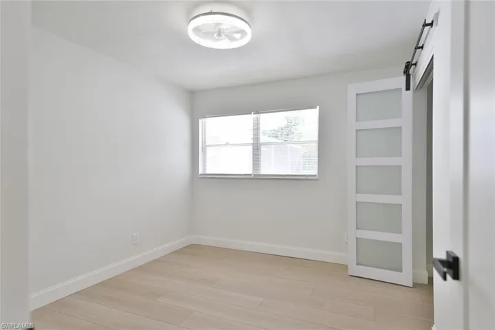 Unfurnished bedroom featuring a barn door and light wood-type flooring