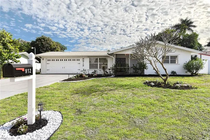 Ranch-style home with an attached garage, driveway, a front lawn, and a sunroom