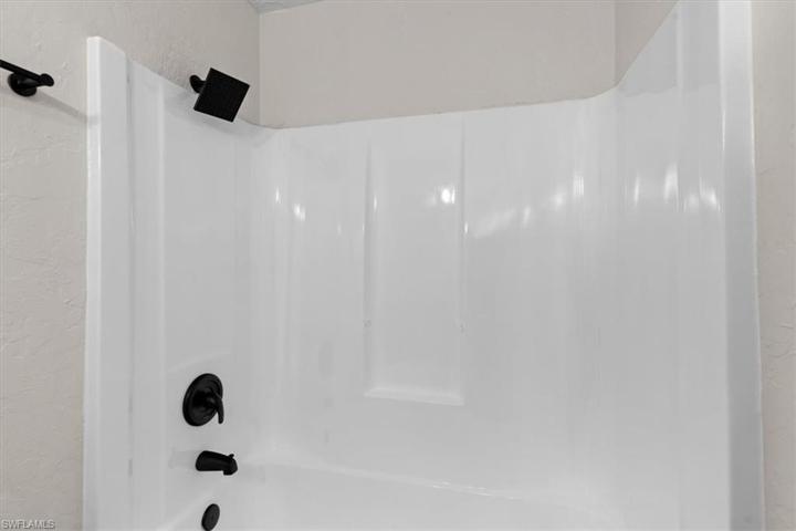 Guest combo bath tub/shower with newly-installed water fixtures