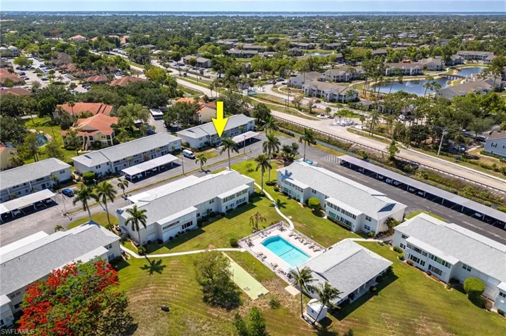 Aerial view of residential area featuring a pool and a nearby body of water