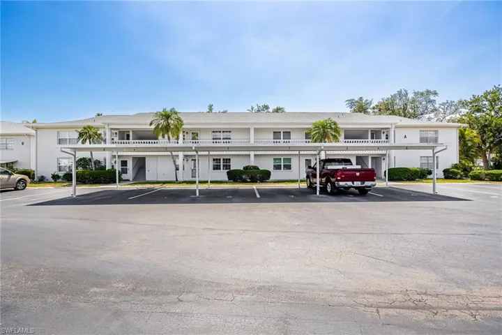 View of property featuring covered and uncovered parking