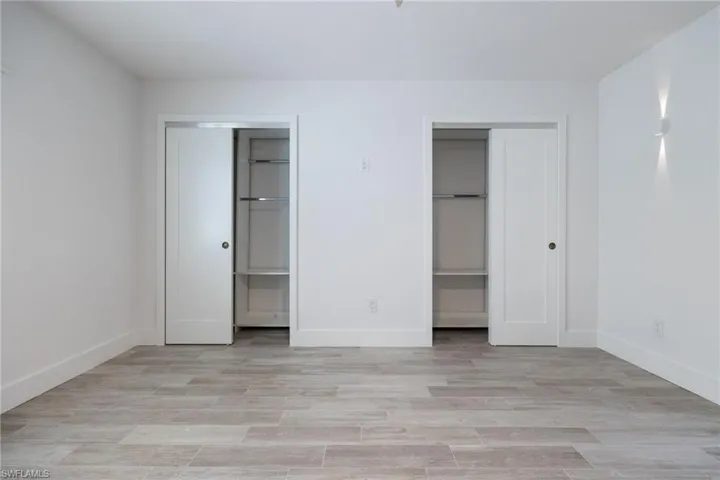 Unfurnished bedroom featuring two closets, baseboards, and light wood finished floors