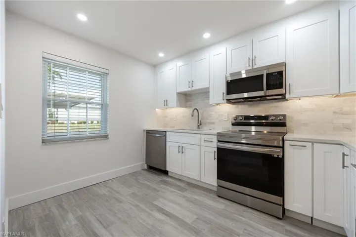Kitchen featuring appliances with stainless steel finishes, a sink, light countertops, tasteful backsplash, and light wood-style floors