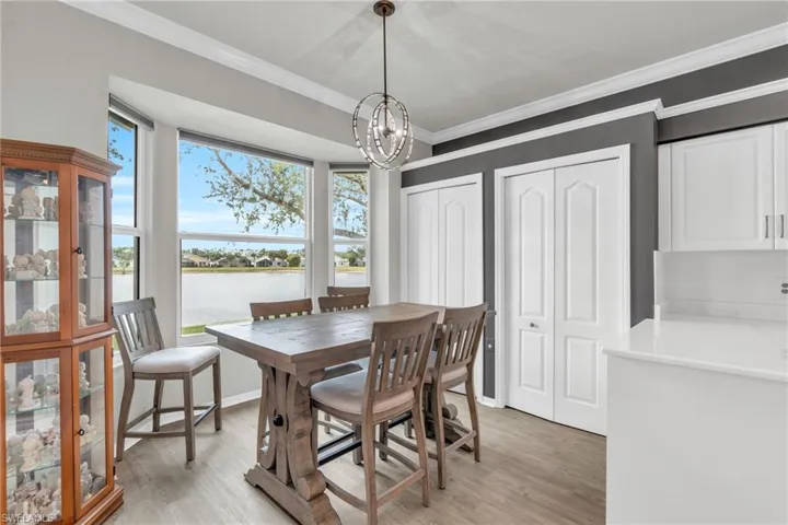 Dining room with a notable chandelier, light hardwood / wood-style flooring, a water view, and ornamental molding