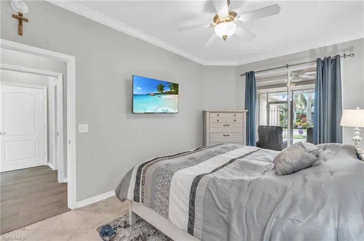 Tiled bedroom featuring ceiling fan, ornamental molding, and access to outside