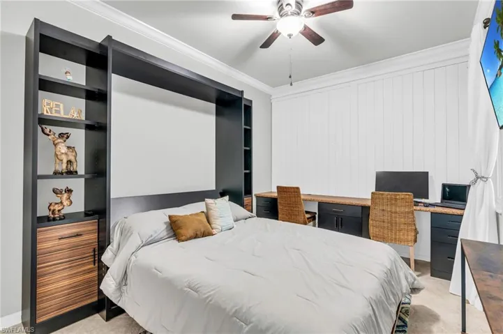 Bedroom featuring ornamental molding, ceiling fan, and built in desk