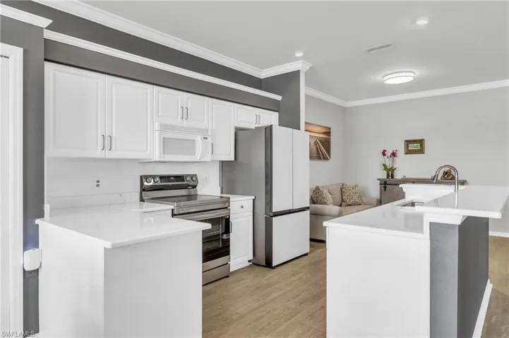 Kitchen featuring light hardwood / wood-style flooring, sink, white cabinets, stainless steel range with electric stovetop, and refrigerator