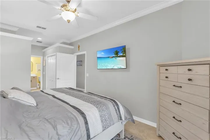 Bedroom with ceiling fan, light tile patterned floors, ensuite bathroom, and ornamental molding